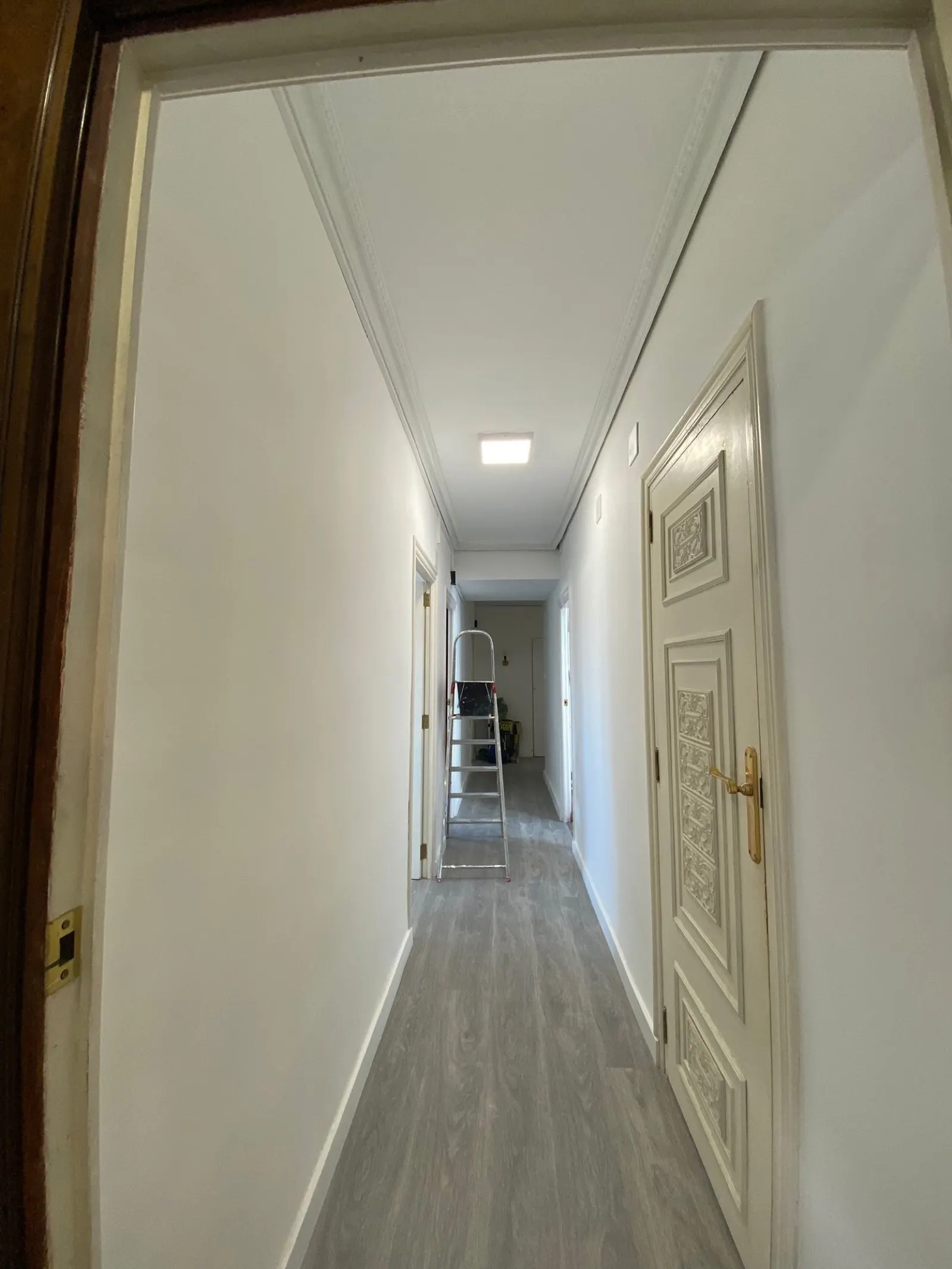 Pasillo recién pintado con una puerta lacada en blanco